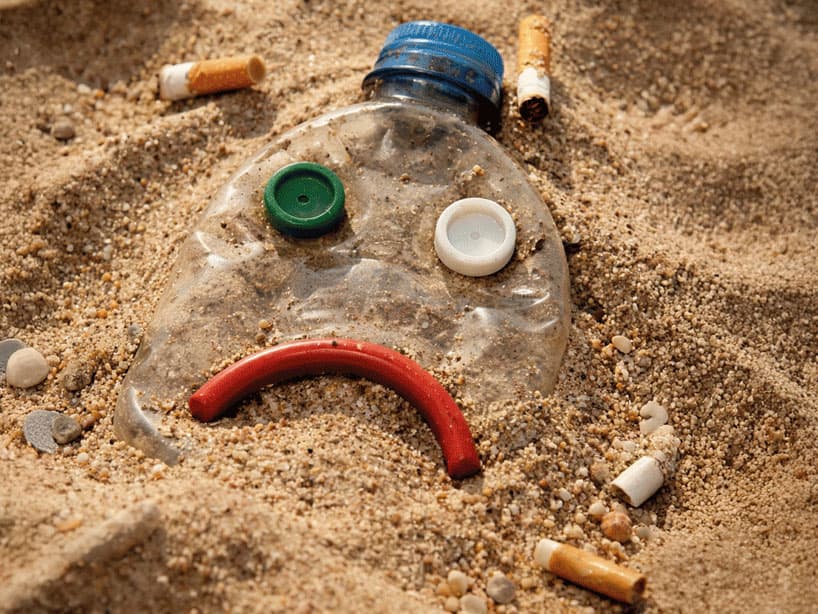 Rifiuti su una spiaggia in una composizione che ritrae una faccina triste